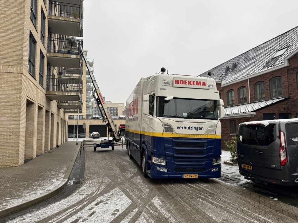 Verhuislift van Hoekema Verhuizingen uitgeschoven tegen een appartementengebouw