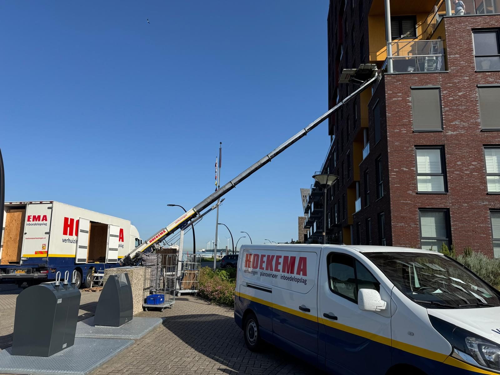 Verhuislift van Hoekema Verhuizingen bij een flat, met de verhuisbus ernaast