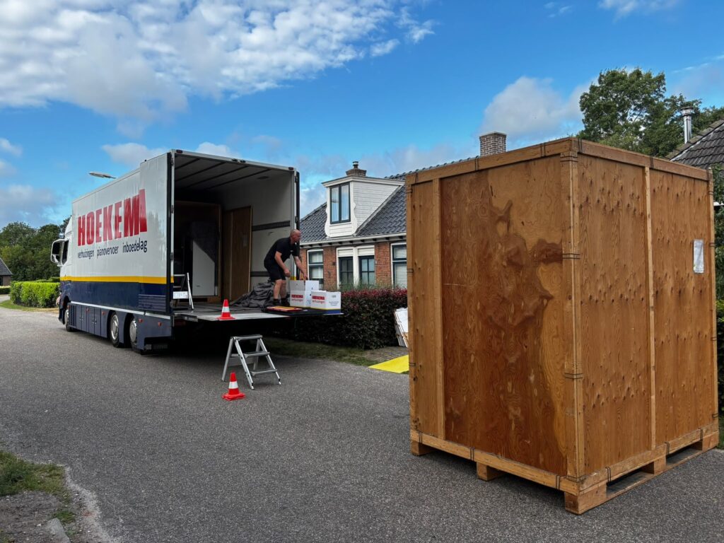 Verhuizer van Hoekema Verhuizingen laadt dozen op de laadklep naast een opslagkist