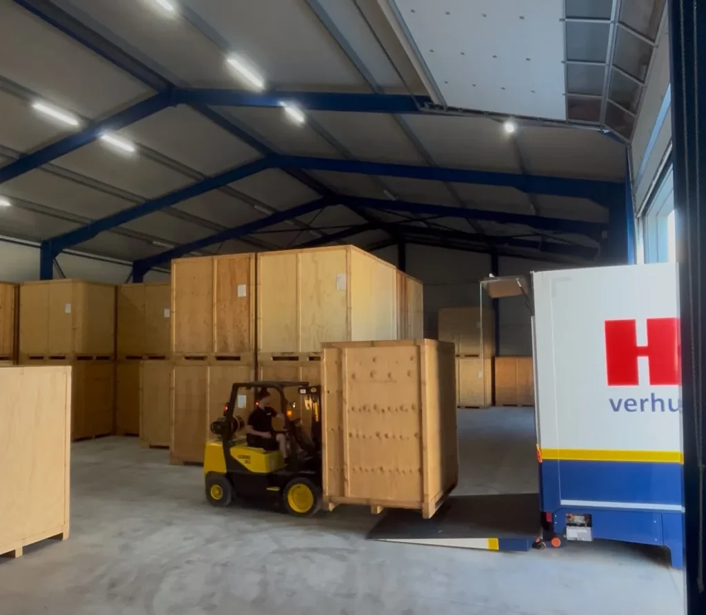 Heftruck van Hoekema Verhuizingen verplaatst een houten kist in de opslaghal